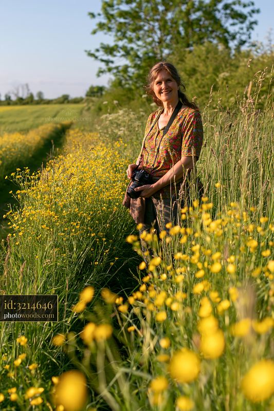 Woman standing by a rural path surrounded by yellow flowers