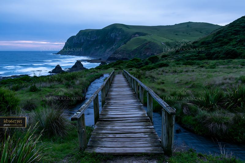 Coastline beneath dramatic cliffs with wooden bridge and hills