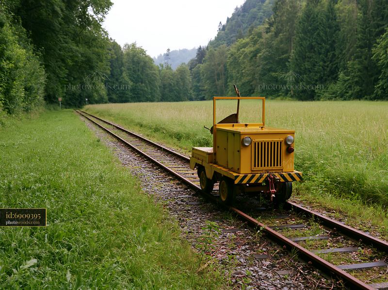 Meadow alongside railway tracks with a yellow maintenance vehicle
