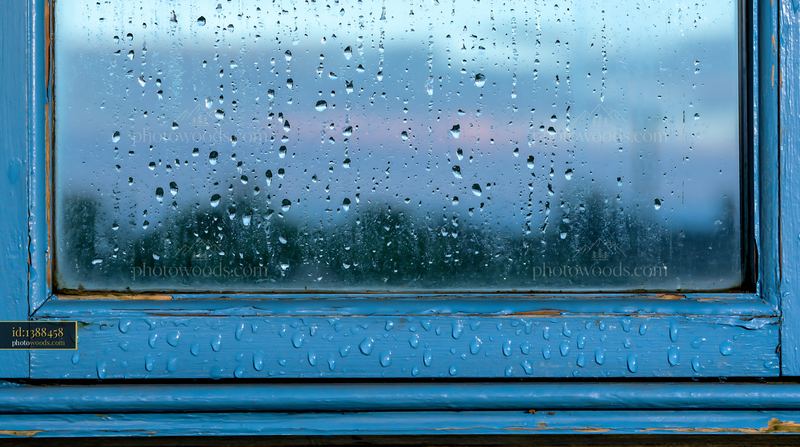 Close-up droplets on rustic glass pane under cloudy sky