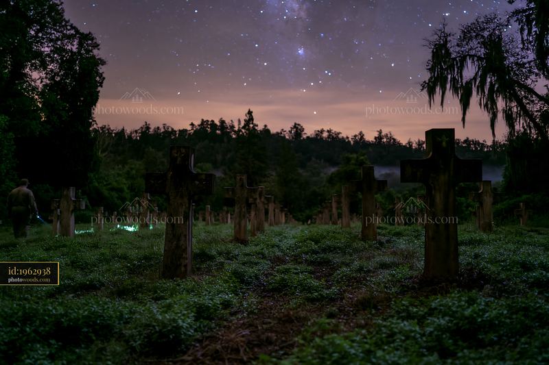 Cross-shaped military grave markers under stars in a dark cemetery