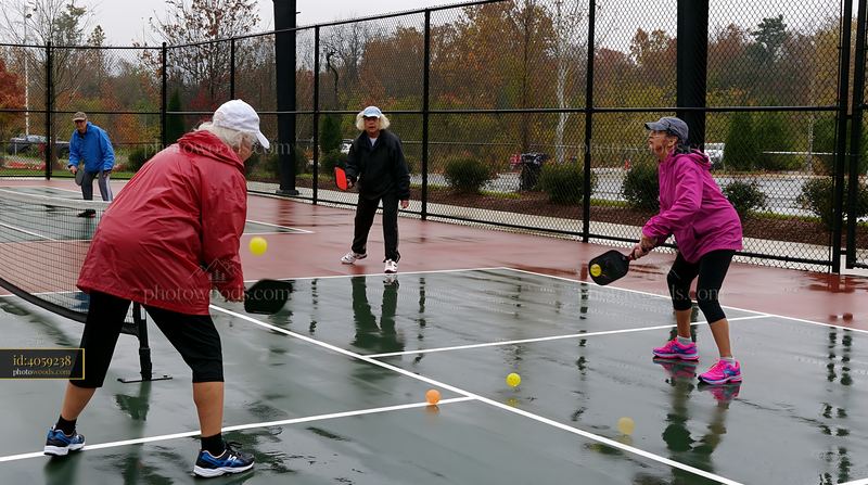 Older friends play pickleball at a rainy court