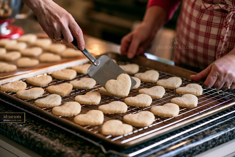 Heart shaped cookies being placed on cooling rack in kitchen