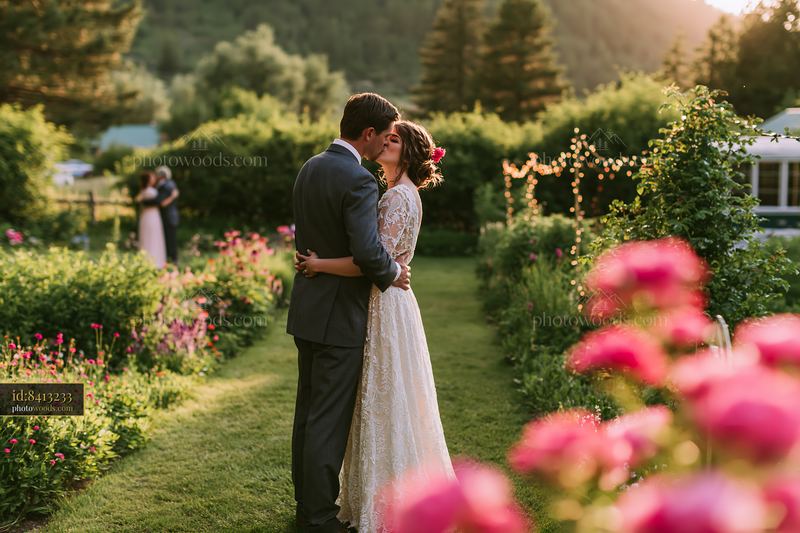 Newlywed couple kissing in a sunlit garden