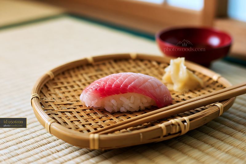 One sushi piece with pickled ginger on a bamboo plate