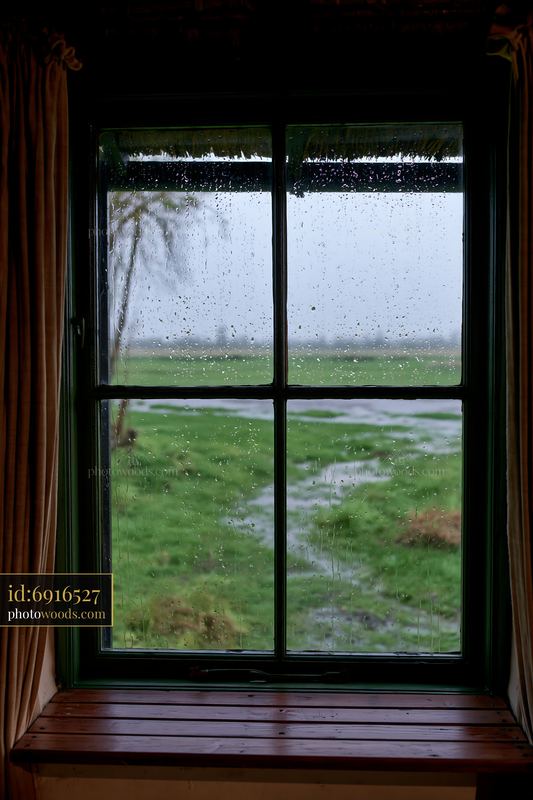 Rain on small cottage window with view of green field