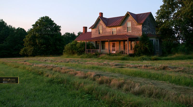 Restored farmhouse exterior with green field and trees