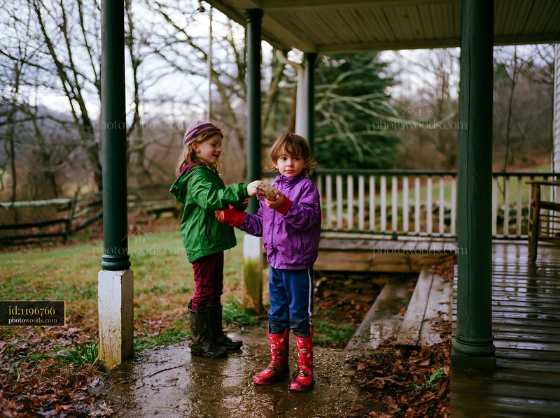 Two children exchanging a Christmas gift on a covered porch