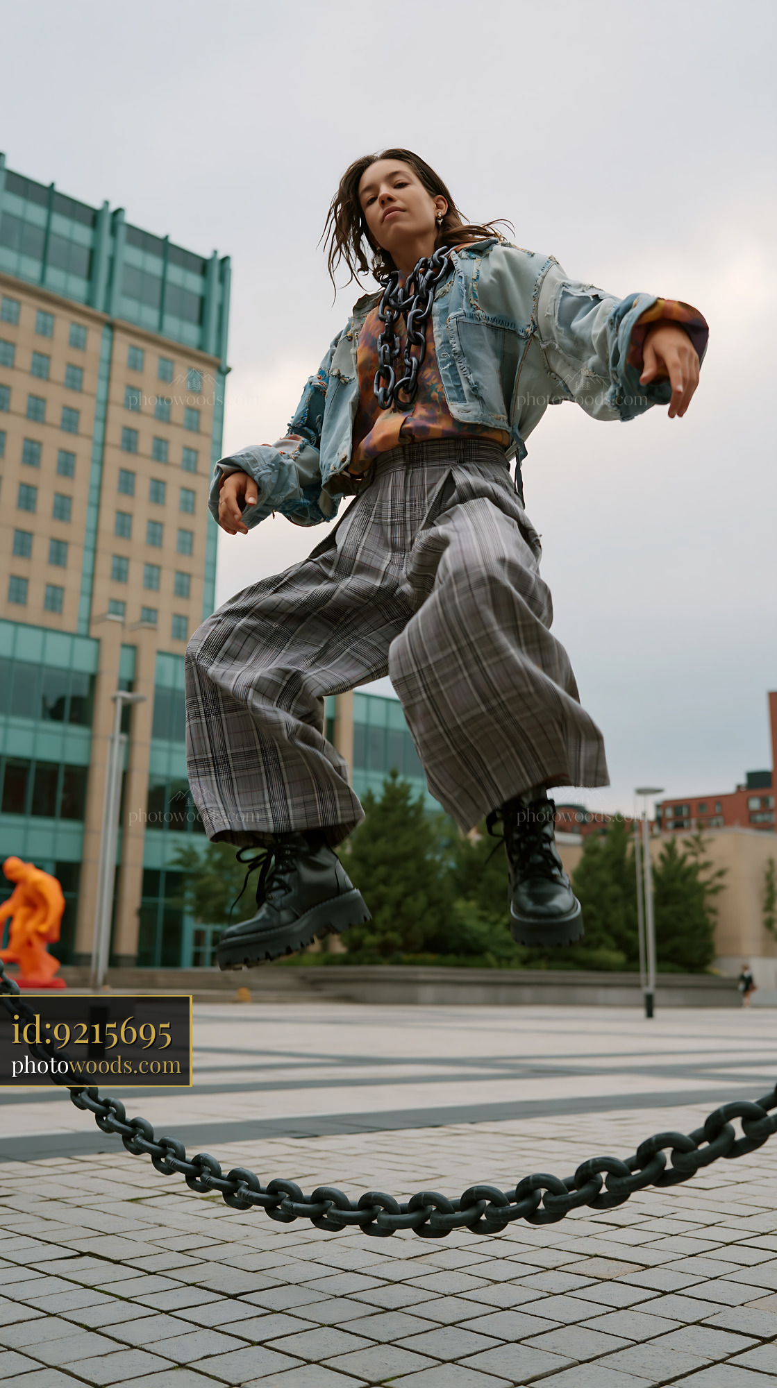 Androgynous Model Jumping Over a Chain in Urban Setting