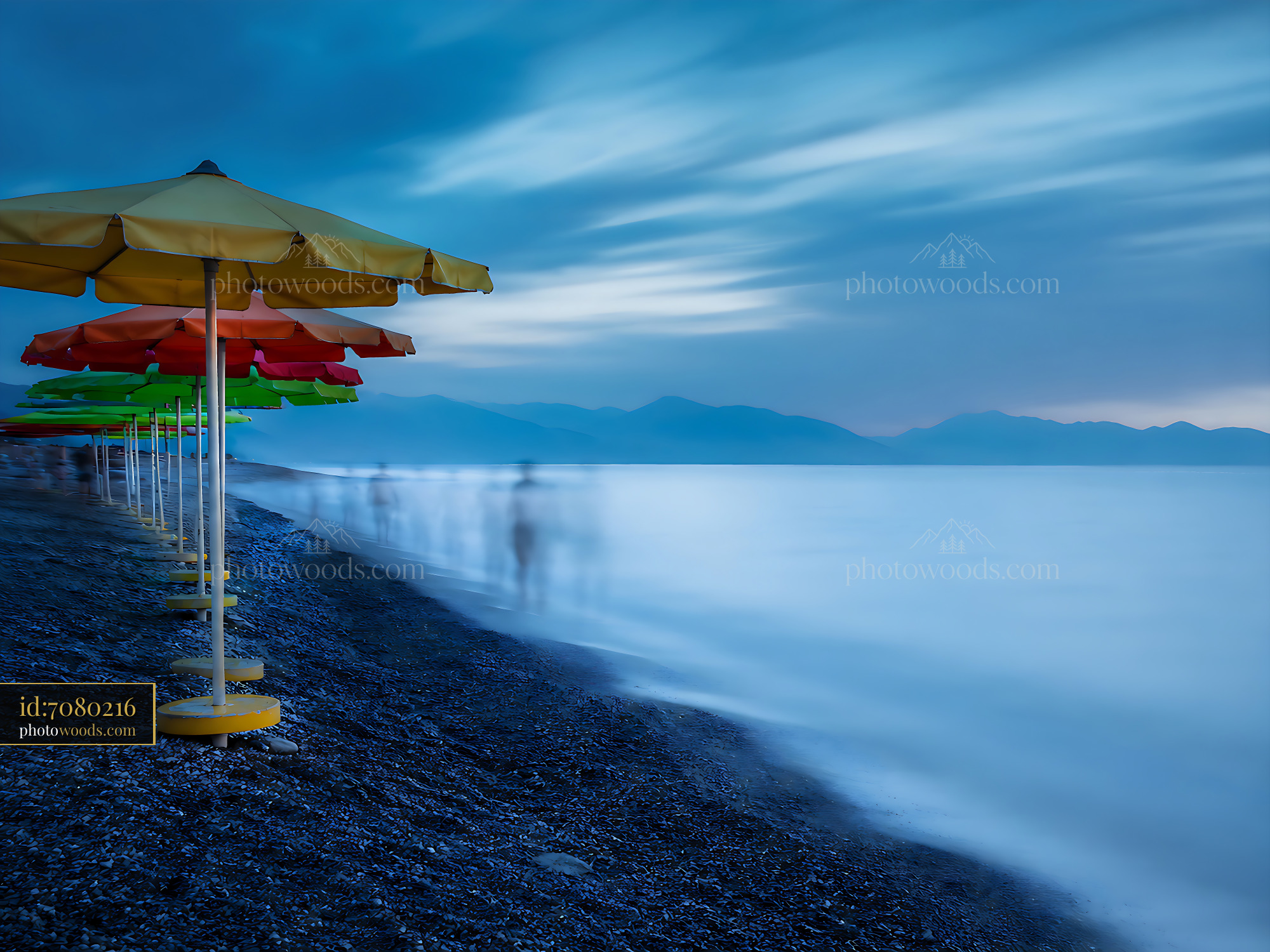 Beach Umbrellas Line the Shore Under Cloudy Sky at Dusk
