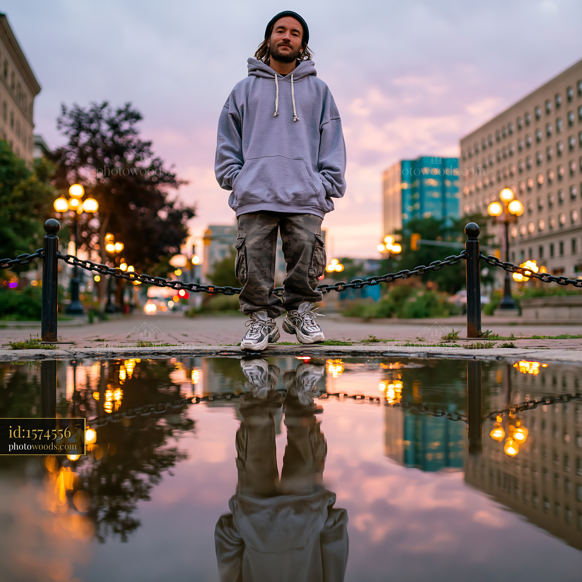 Confident Young Man Standing in Oversized Hoodie by Urban Reflection