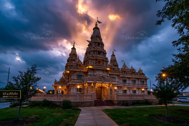 Ornate Hindu temple illuminated beneath dramatic evening clouds