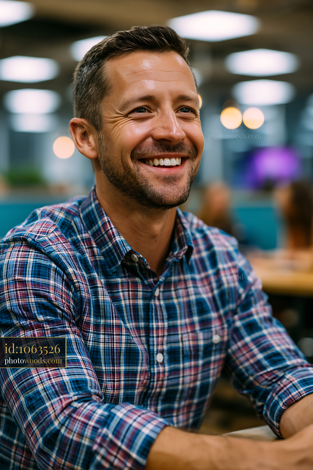 Man Smiling in a Checkered Shirt at a Casual Setting