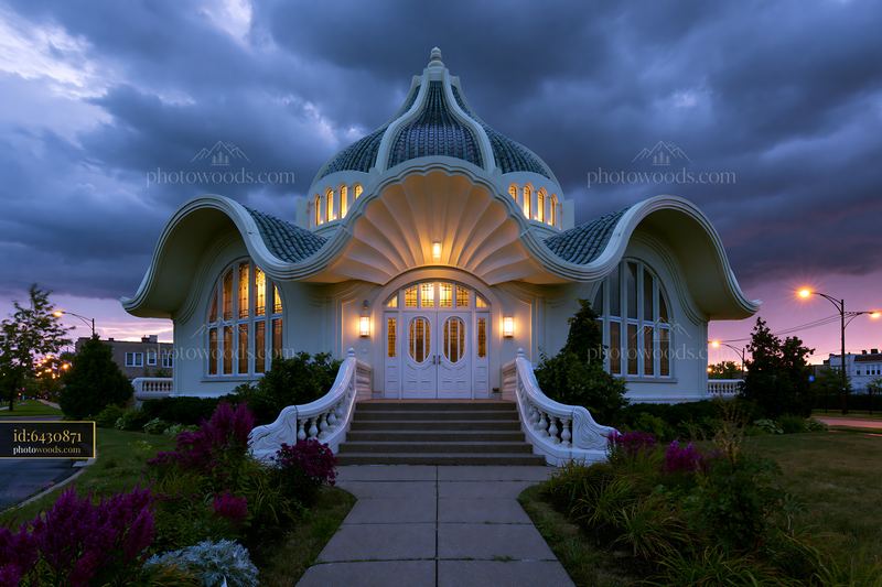Ornate illuminated building beneath dramatic evening clouds