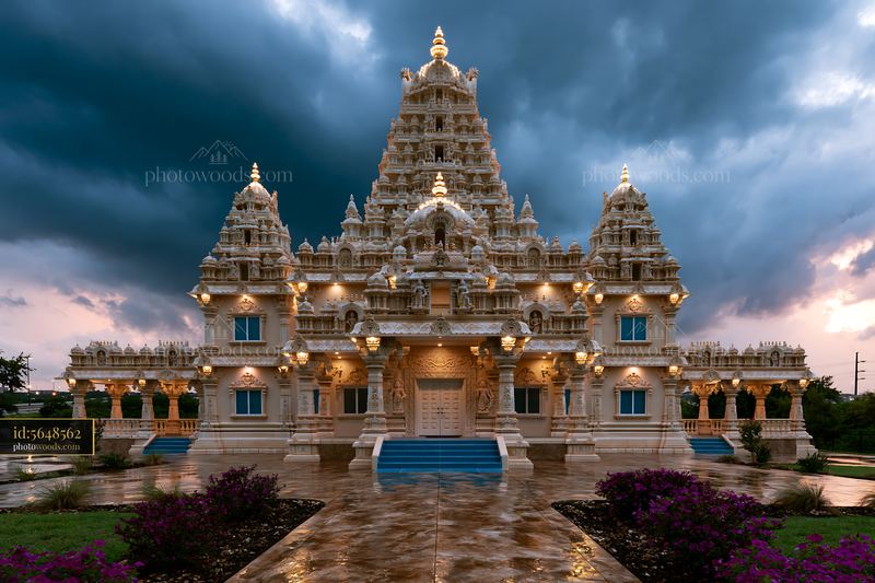 Ornate Hindu temple illuminated beneath dramatic storm clouds